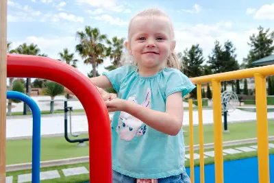 Young child smiling at a colourful playground